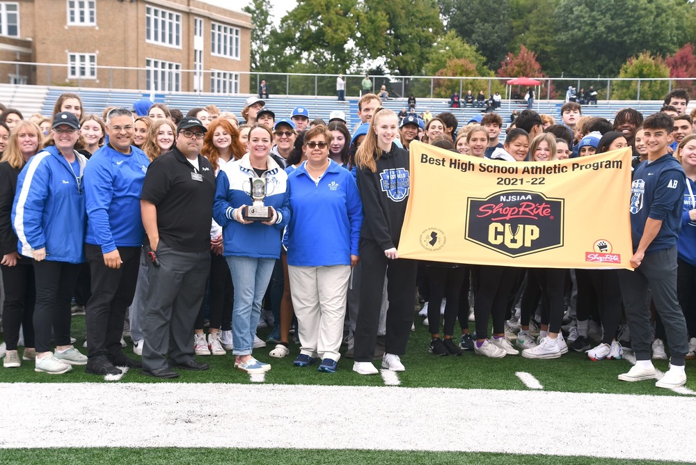 School officials, student-athletes and others pose with ShopRite Cup and banner