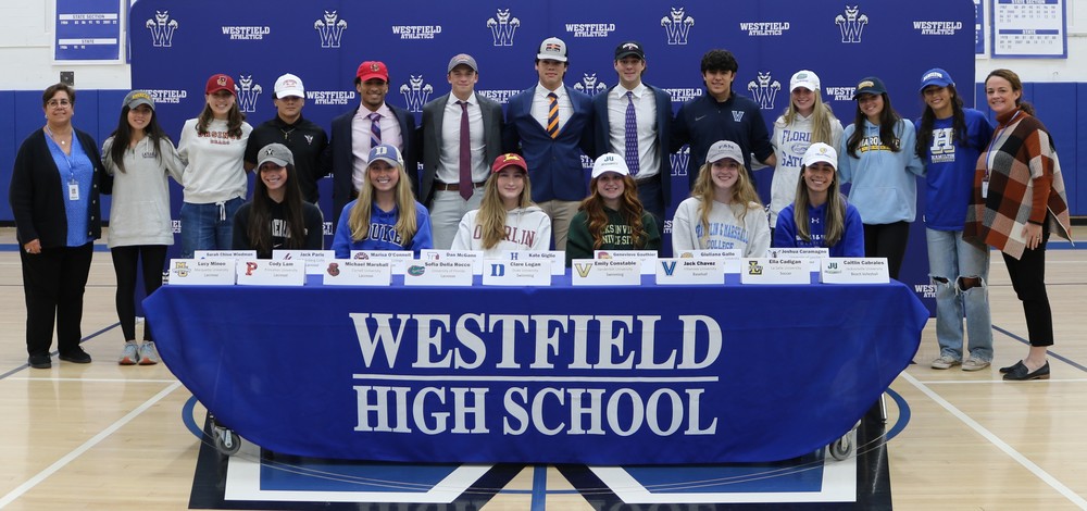Group photo of student athletes with WHS banner