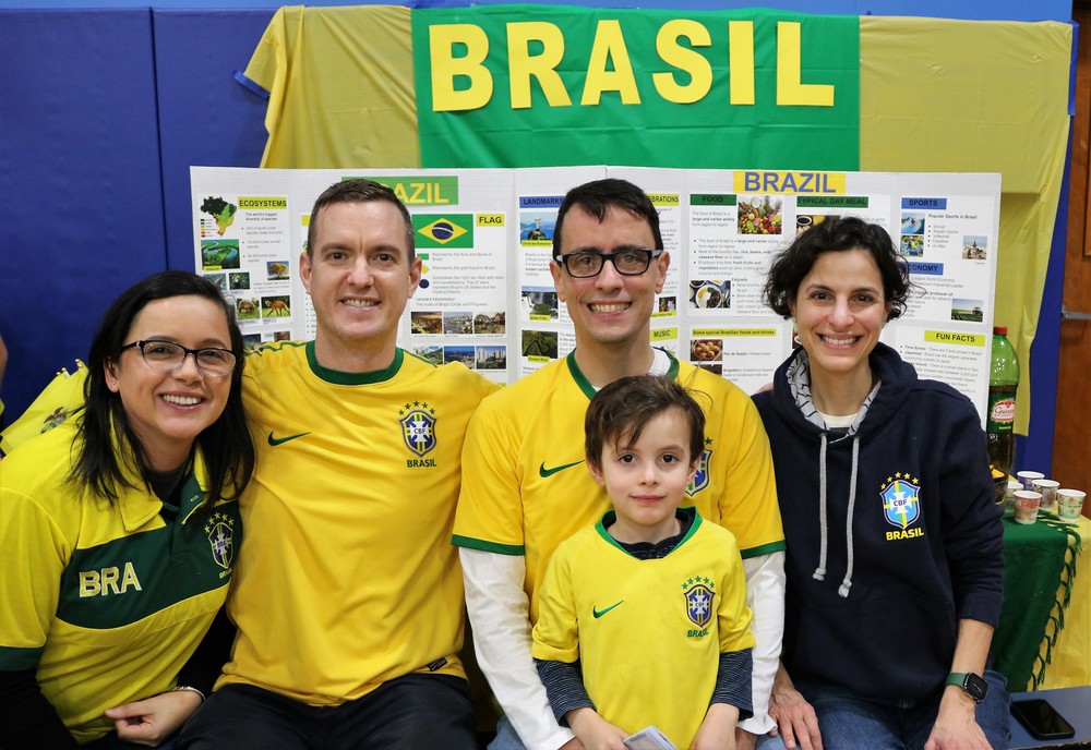 Family smiles for camera in front of Brasil display during Multicultural festival