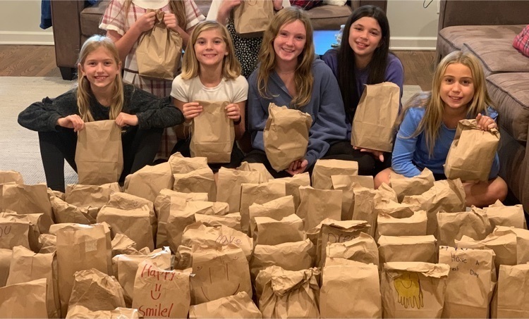 Franklin  girl scouts stand in front of table filled with bag lunches