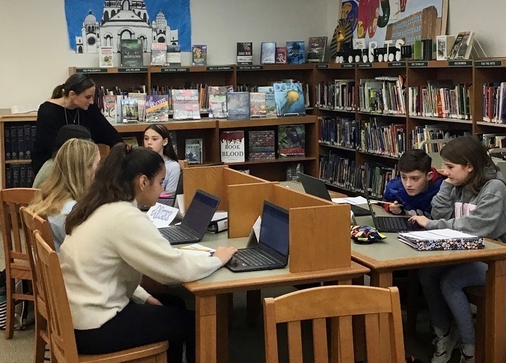 RIS  librarian Megan Lynn works with 6th graders on their laptops