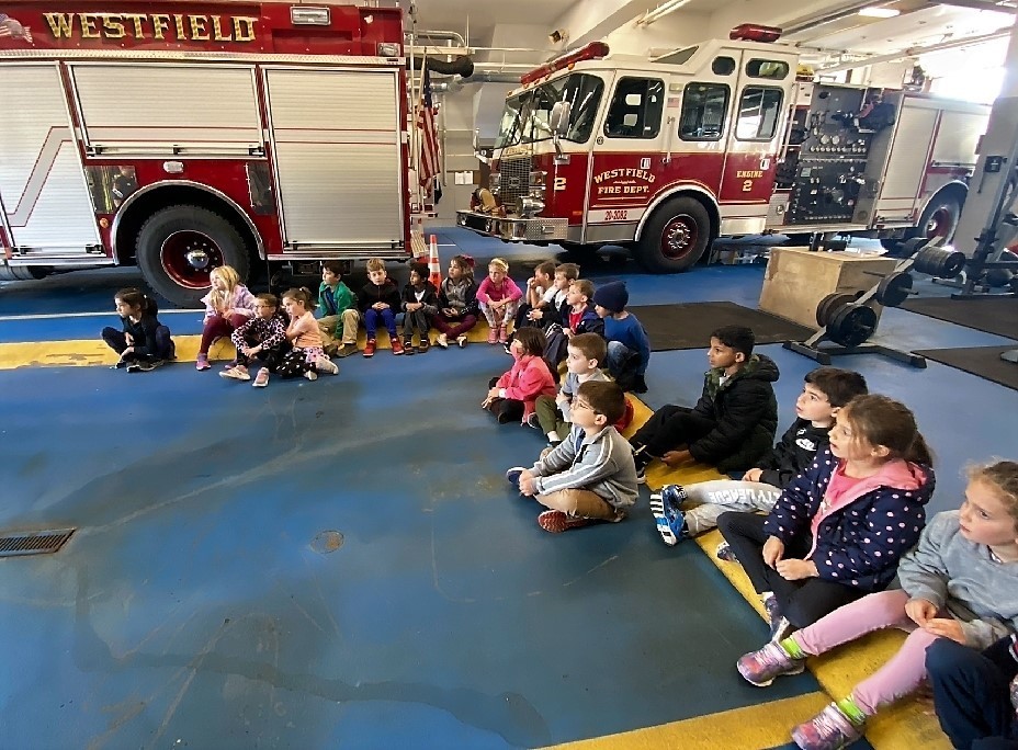 McKinley 1st graders sit on the firehouse floor as they listen to firefighters