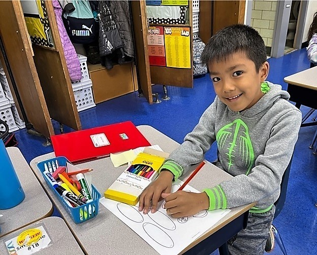 Jefferson student smiles at camera while working on art work