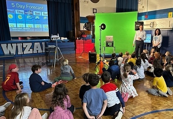 Wilson students sit on floor during an assembly with meterologists