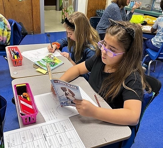 Two Jefferson 3rd graders sit at desk reading books