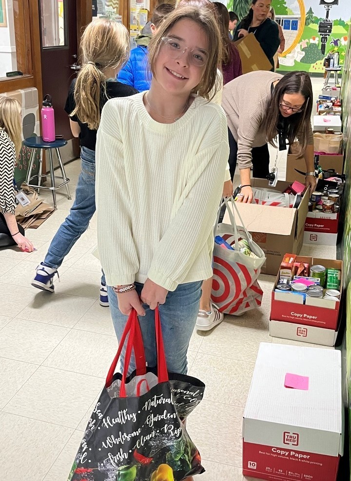 Jefferson student smiles and holds bag during Thanksgiving Food Drive