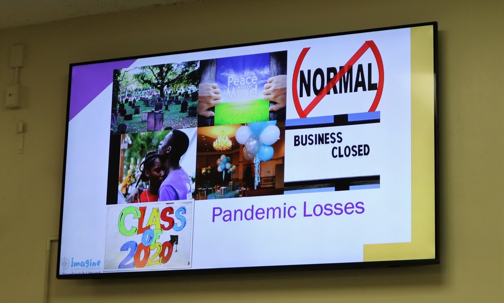 Photo of TV screen with presentation slide regarding pandemic losses