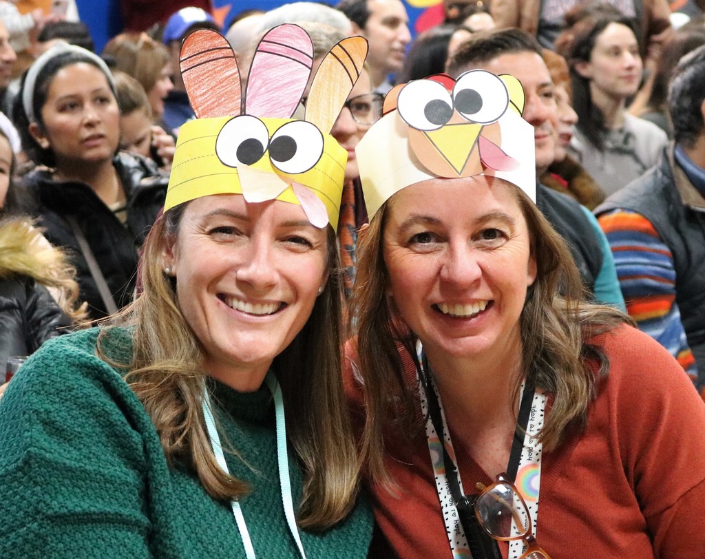 Two Washington teachers smile and wear turkey hats
