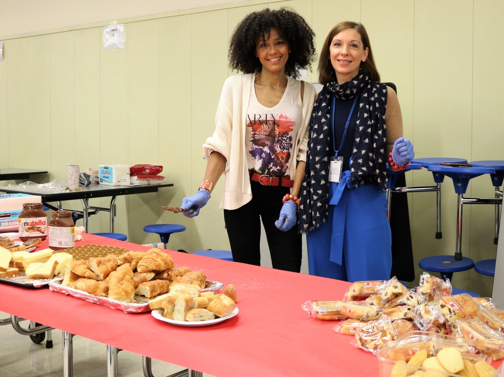 RIS French teachers stand in front table of breakfast items