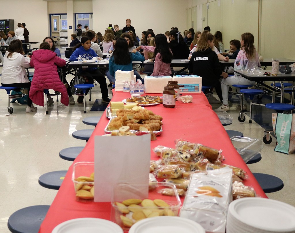 Table full of French breakfast items and students in the background enjoying the feast