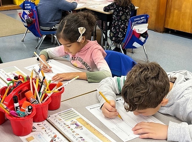 Two Jefferson 1st graders work at their desks with number lines for addition and subtraction