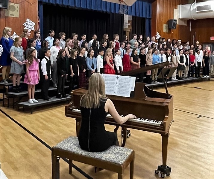 Music teacher plays the piano as elementary students at Tamaques sing during holiday concert