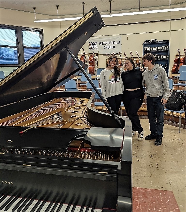 Three WHS choral students pose with newly refurbished Steinway
