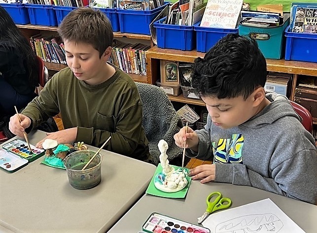 Two McKinley 5th grade boys paint clay landscapes in art