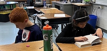 Two  Jefferson 4th graders sit side by side at desks to read