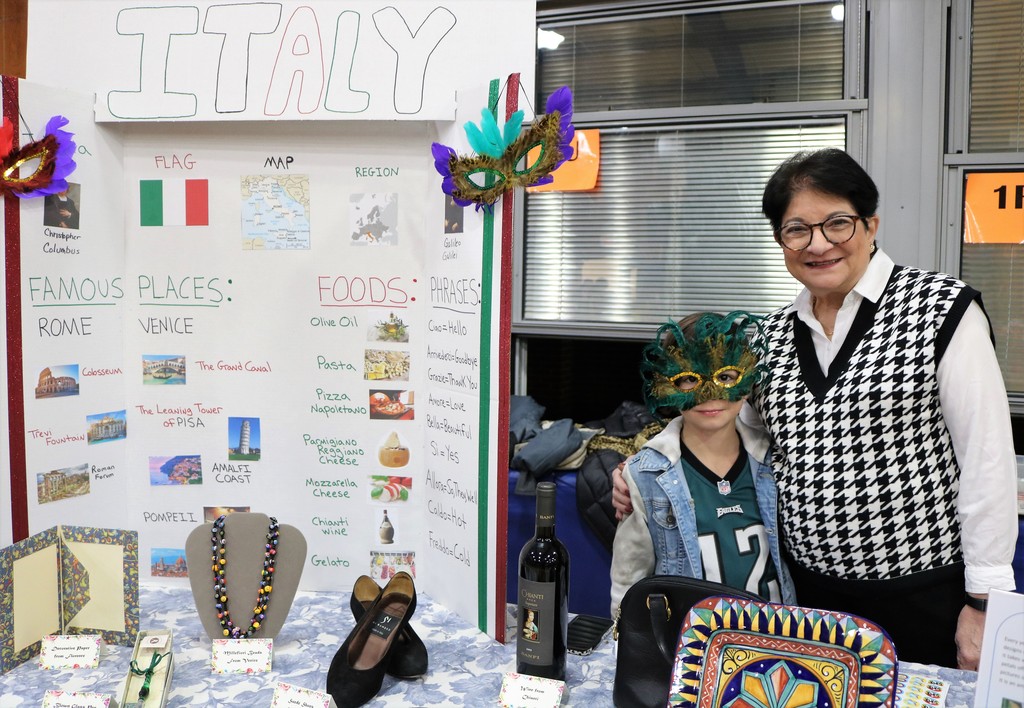 Tamaques grandparent and grandson stand with Italy display at multicultural festival