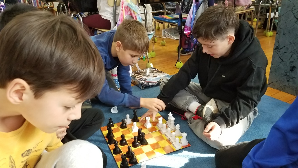 4th graders playing chess on the floor during indoor recess