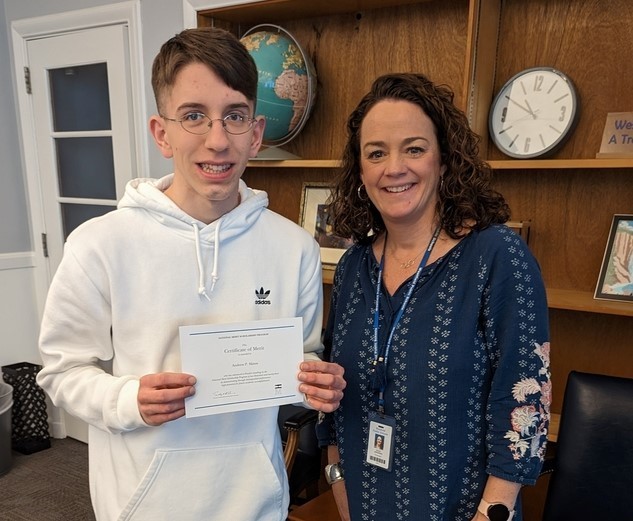 WHS Merit Finalist holds certificate and poses for picture with principal