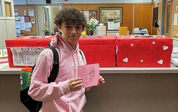 EIS student holds pink card in front of red nomination boxes