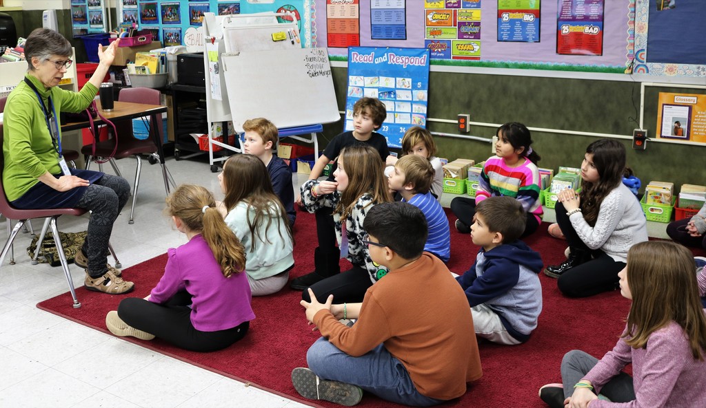 Poet-in-Residence Luray Gross tells a story to third graders sitting on floor