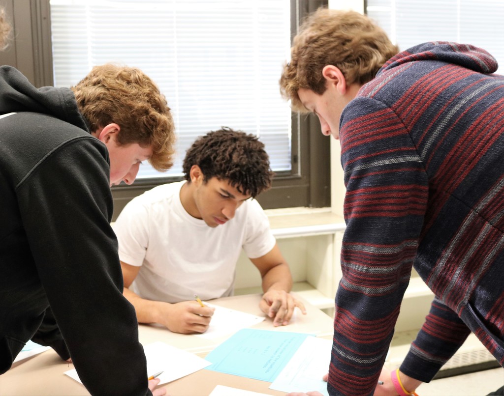 Three WHS students work together at desk