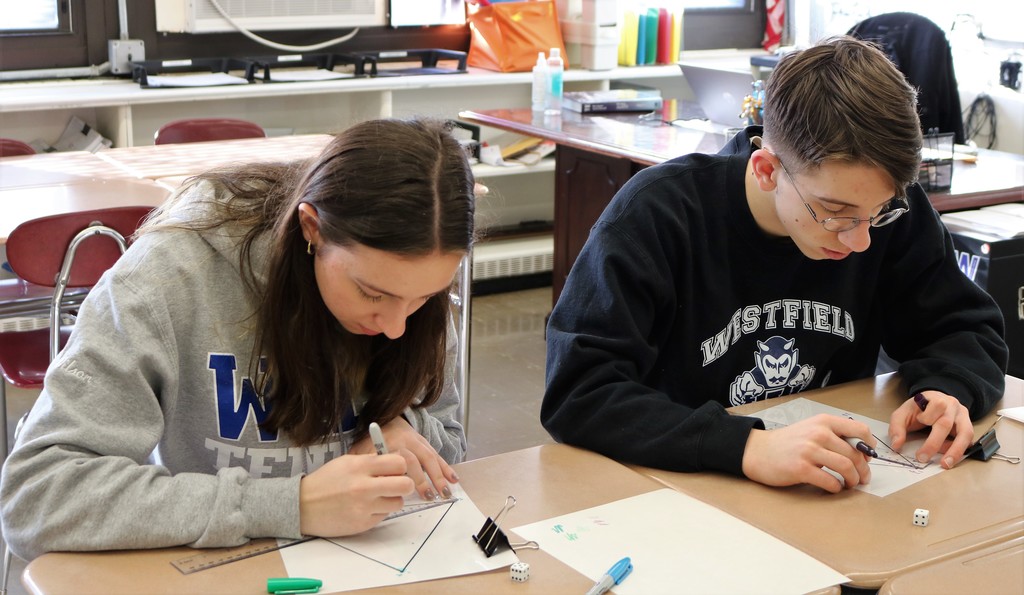 Two WHS students draw graph at desk