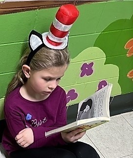 Jefferson student wearing a Cat in the Hat hat reading