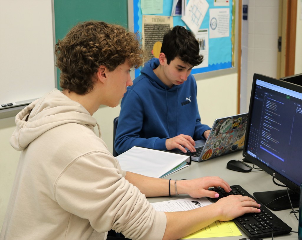 Two high school students work on coding project