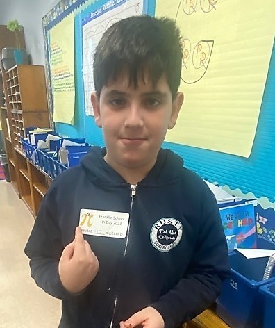 Franklin 5th grader point to Pi Day sticker on his jacket
