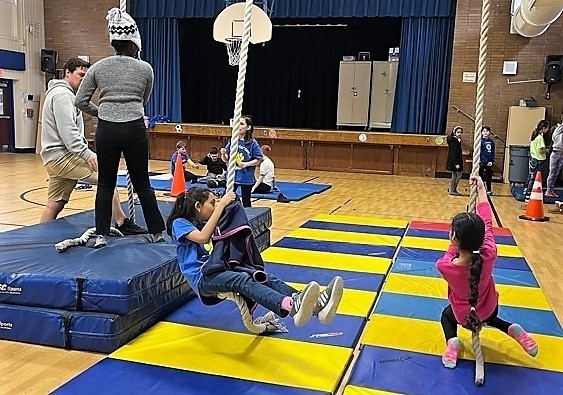 Two Jefferson students swing on rope during gymnastics unit