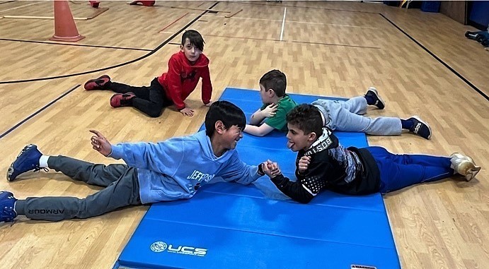 Jefferson students arm wrestle on gymnastics mat