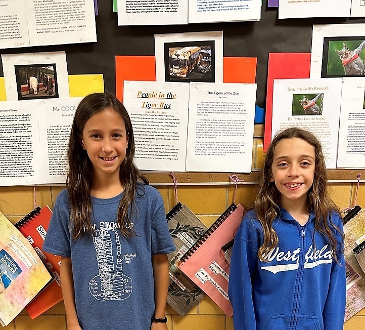 Two Wilson 4th graders in front of bulletin board with classmates projects