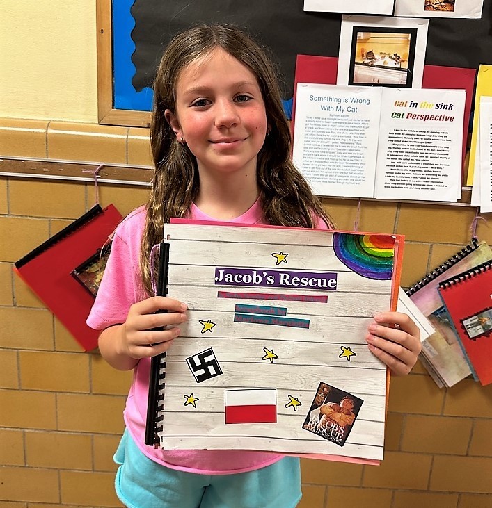 Wilson 4th grader holds her historical fiction project and smiles for camera