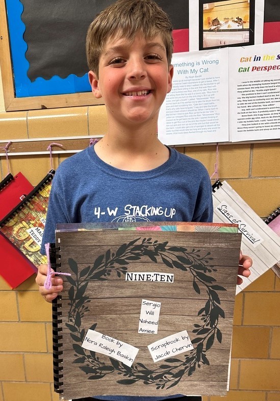 Wilson 4th grader holds his historical fiction project and smiles for camera