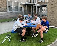 Group of RIS students at outdoor table working on science lab