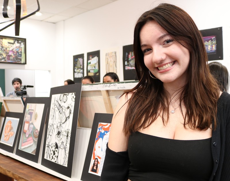 WHS 12th grader poses for picture in front of her artwork